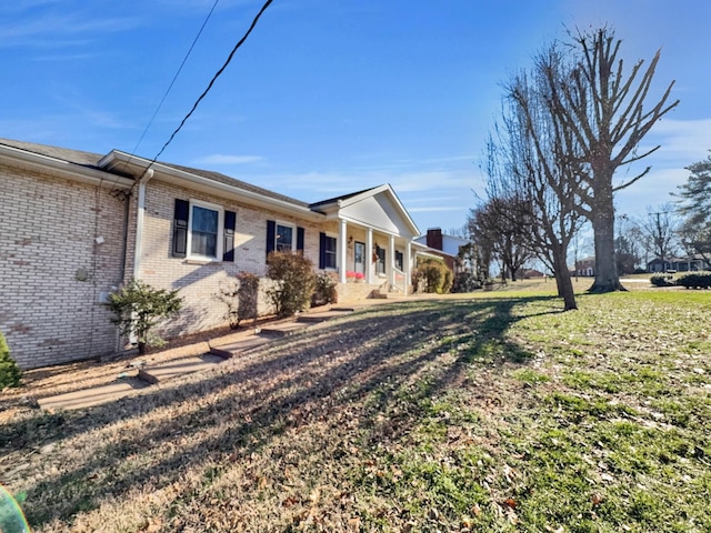 view of side of home with a yard and brick siding