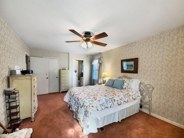 bedroom featuring wallpapered walls, baseboards, dark carpet, and a ceiling fan