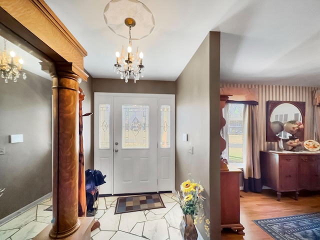 foyer featuring light wood-style floors, decorative columns, and a notable chandelier