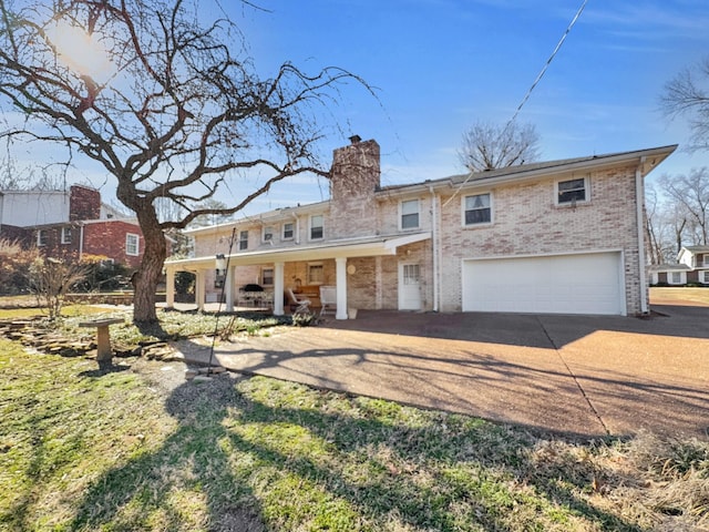 view of front of property featuring a porch, an attached garage, brick siding, concrete driveway, and a chimney