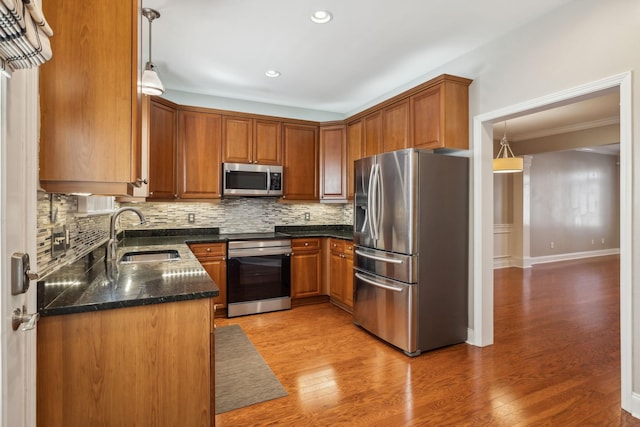 kitchen featuring backsplash, stainless steel appliances, a sink, and light wood finished floors