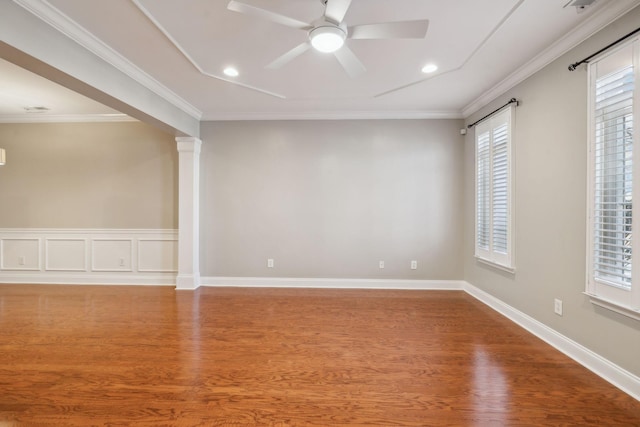 spare room featuring ceiling fan, crown molding, ornate columns, and wood finished floors