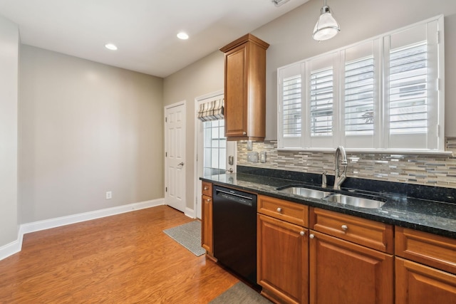 kitchen with brown cabinetry, dishwasher, light wood-style flooring, backsplash, and a sink