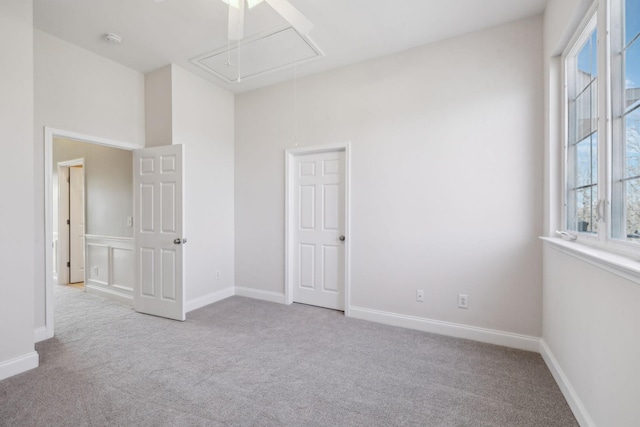 unfurnished bedroom with attic access, carpet, and baseboards