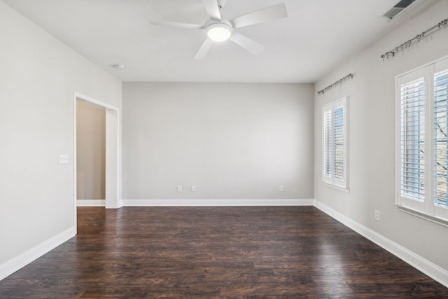 unfurnished room featuring dark wood-style floors, a wealth of natural light, baseboards, and a ceiling fan