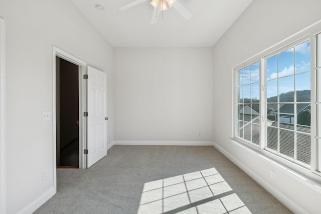 carpeted spare room with a ceiling fan and baseboards