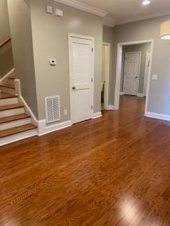 interior space featuring wood finished floors, visible vents, baseboards, stairs, and crown molding