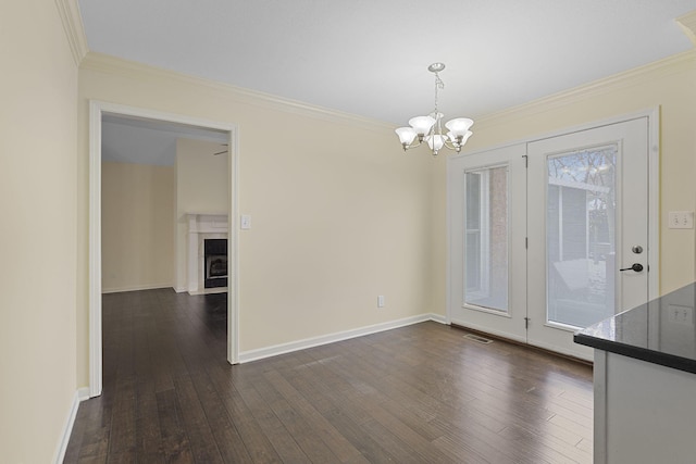 unfurnished dining area featuring dark wood-style floors, ornamental molding, baseboards, and an inviting chandelier