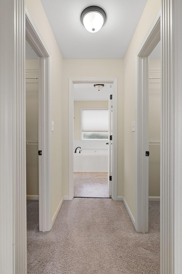 corridor with carpet flooring and baseboards