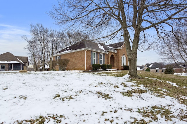 snow covered property featuring a garage and brick siding