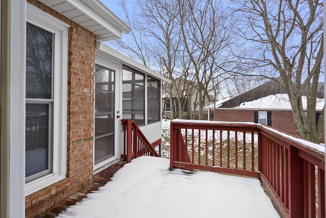 snow covered deck featuring a sunroom