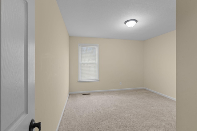 carpeted spare room featuring baseboards and visible vents