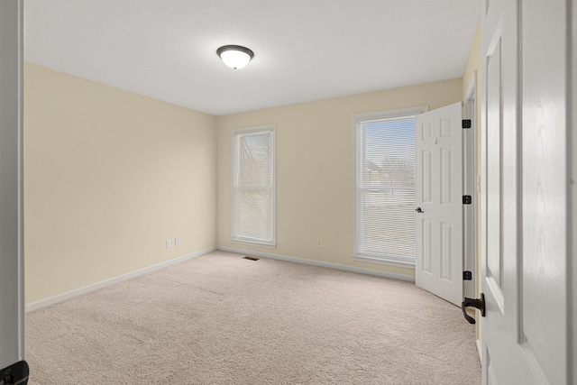 spare room with carpet, visible vents, and baseboards