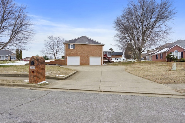 view of side of property with an attached garage, driveway, stairs, and brick siding