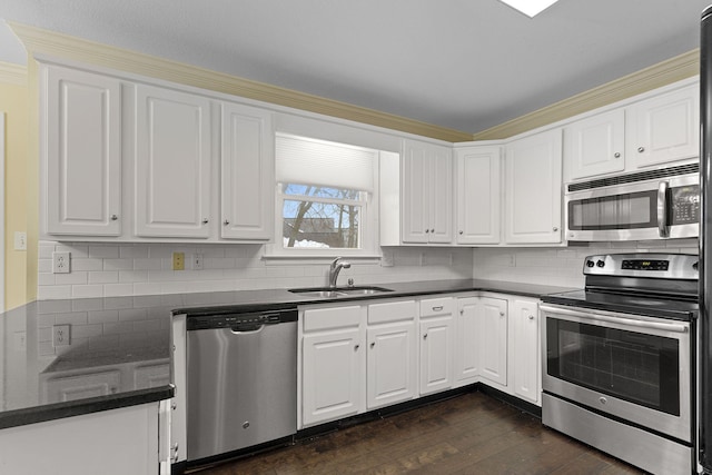 kitchen with dark countertops, dark wood-style floors, stainless steel appliances, white cabinetry, and a sink