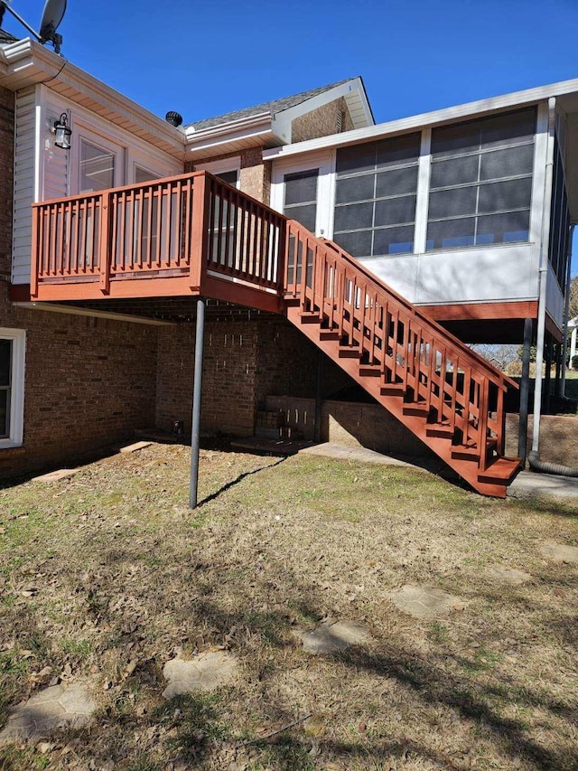 rear view of house with brick siding, a deck, and stairs