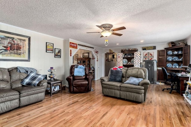 living area with ceiling fan, a textured ceiling, light wood-style flooring, and crown molding