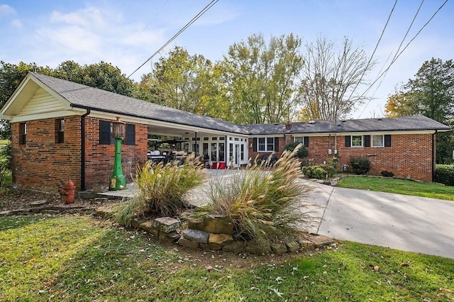 ranch-style house with a carport, concrete driveway, brick siding, and a front lawn