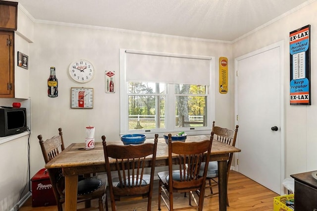 dining area with light wood finished floors and crown molding