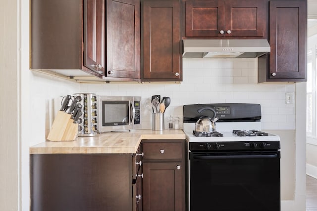 kitchen with stainless steel microwave, gas range oven, decorative backsplash, and under cabinet range hood