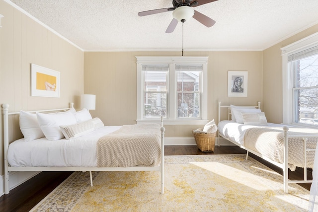 bedroom featuring dark wood finished floors, ornamental molding, ceiling fan, a textured ceiling, and baseboards