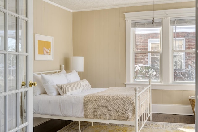 bedroom featuring a textured ceiling, ornamental molding, and wood finished floors