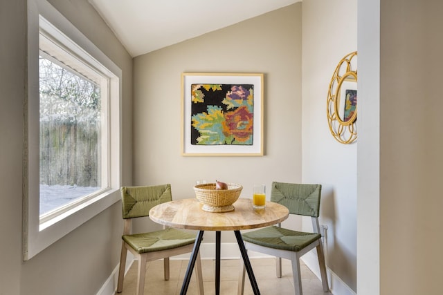 dining room with breakfast area, lofted ceiling, baseboards, and light tile patterned floors