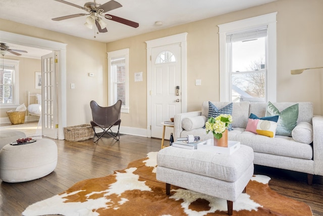 living area featuring ceiling fan, baseboards, and dark wood finished floors