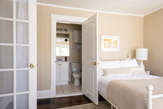 bedroom with a textured ceiling, ornamental molding, wood finished floors, and visible vents