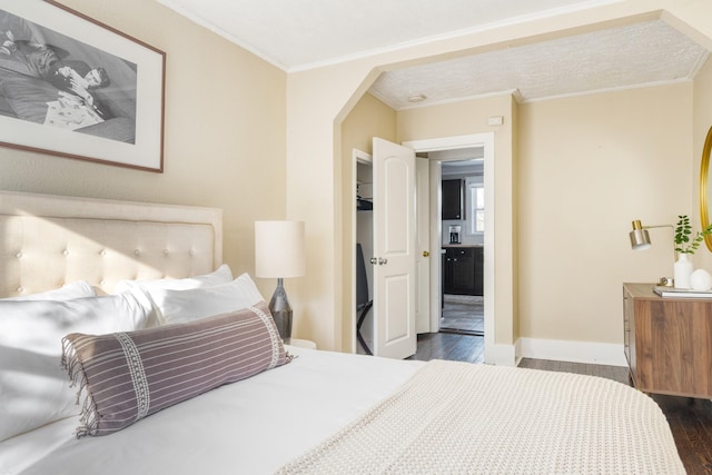 bedroom with dark wood-style floors, arched walkways, crown molding, and baseboards