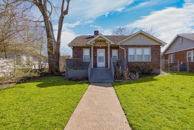 bungalow-style home with brick siding, a chimney, a front lawn, and roof with shingles