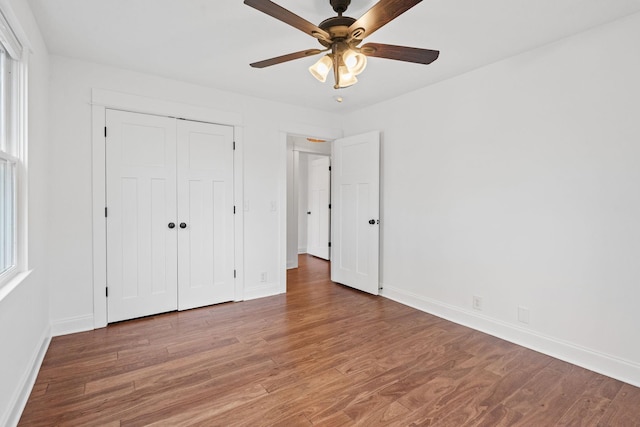 unfurnished bedroom with a ceiling fan, a closet, baseboards, and wood finished floors