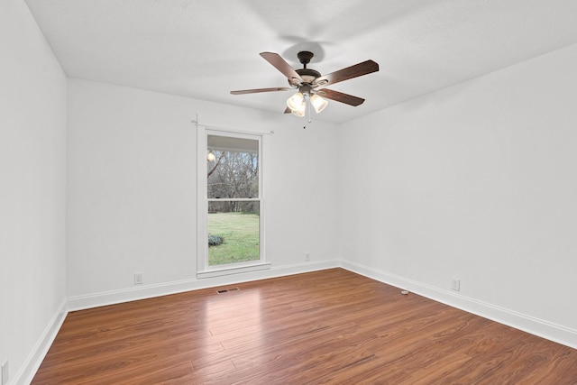 spare room with ceiling fan, wood finished floors, visible vents, and baseboards