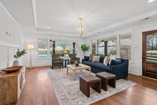 living area featuring a textured ceiling, wood finished floors, a raised ceiling, and a decorative wall