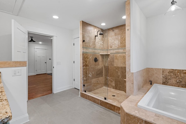 bathroom with baseboards, a shower stall, a bath, and recessed lighting