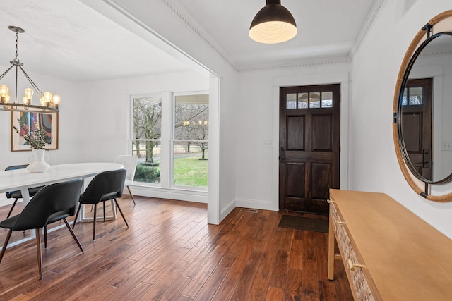 foyer with baseboards, ornamental molding, dark wood-style flooring, and an inviting chandelier