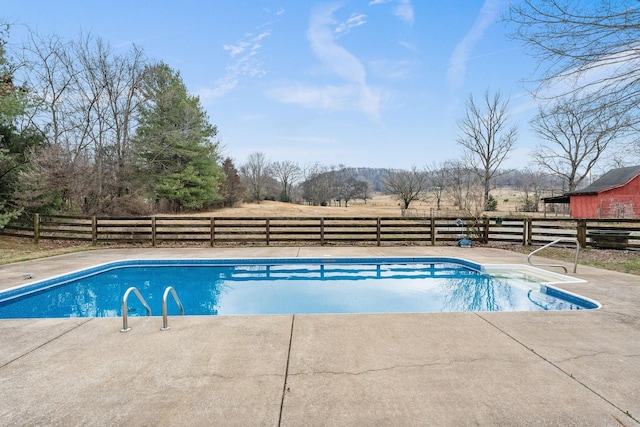 view of swimming pool with a rural view, a patio area, fence, and a fenced in pool