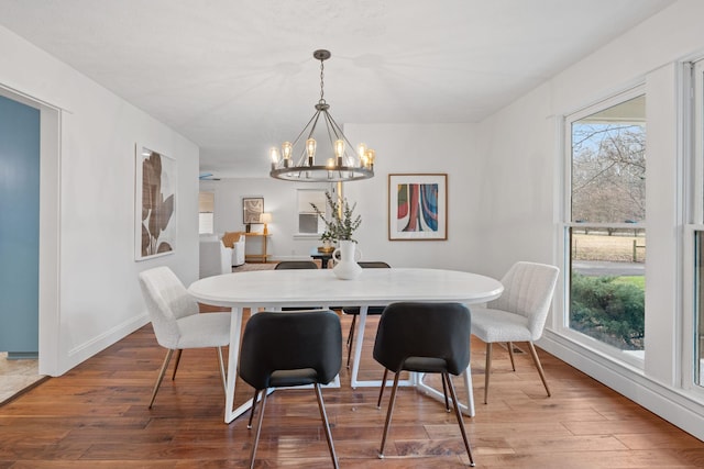 dining area featuring an inviting chandelier, baseboards, and wood finished floors