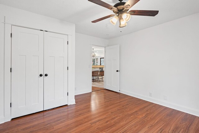 unfurnished bedroom with a ceiling fan, a closet, baseboards, and wood finished floors