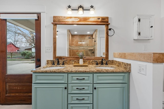 bathroom with a tile shower, double vanity, and a sink