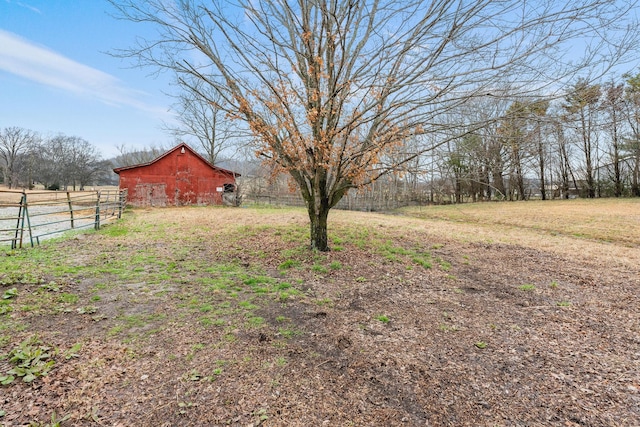 view of yard featuring an outbuilding, a rural view, a barn, and fence