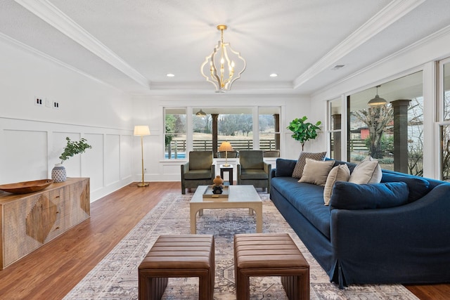 living area with a raised ceiling, a decorative wall, and wood finished floors