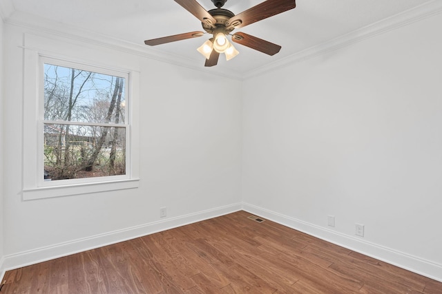 empty room featuring wood finished floors, visible vents, baseboards, a ceiling fan, and crown molding