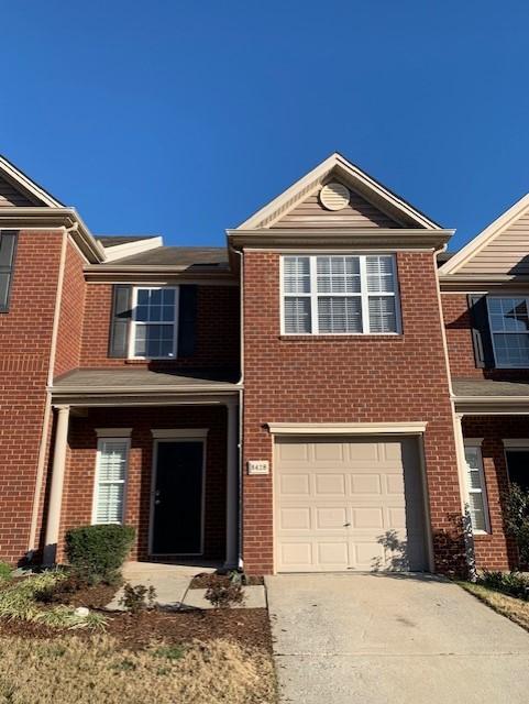 multi unit property featuring driveway, brick siding, and an attached garage