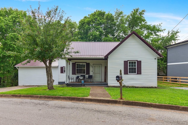 view of front of house featuring covered porch, metal roof, fence, and a front lawn