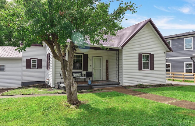 view of front facade with metal roof, fence, a front lawn, and covered porch