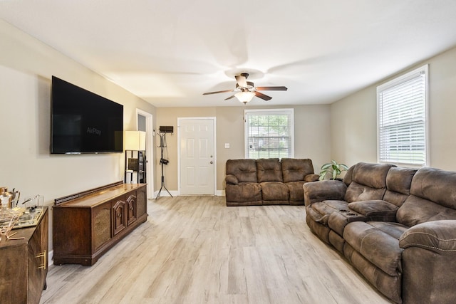 living area featuring light wood finished floors, baseboards, and a ceiling fan