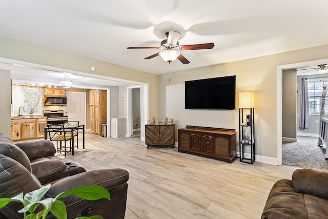 living room with light wood-style flooring, baseboards, and a ceiling fan