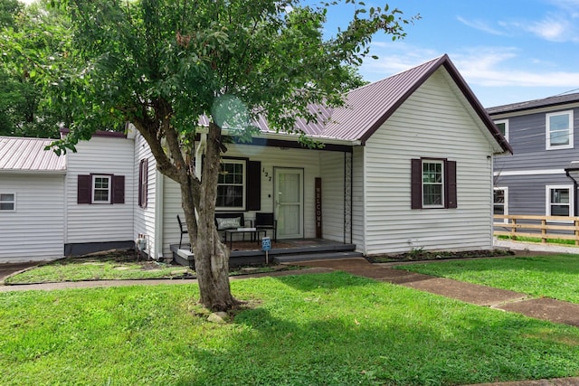 view of front of home with metal roof, a front lawn, a porch, and fence