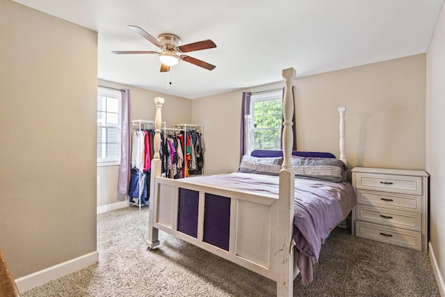 bedroom with light carpet, baseboards, a ceiling fan, a walk in closet, and a closet